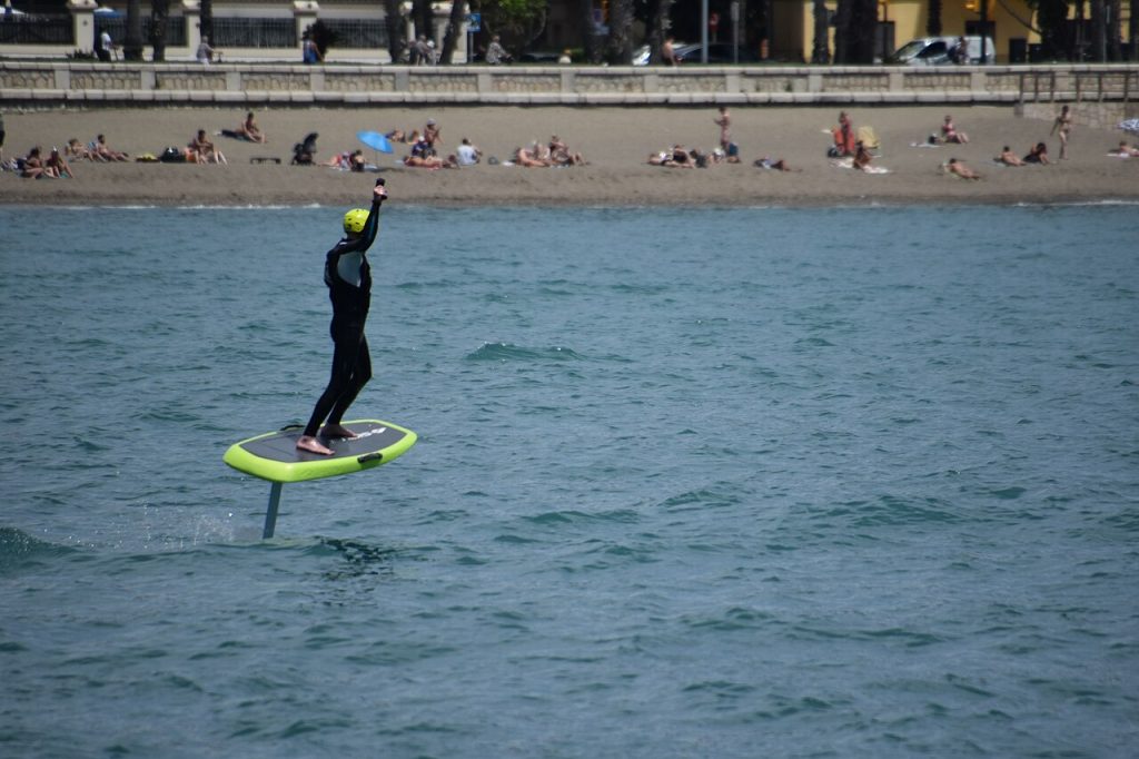 A rider flying a foil board close to the beach